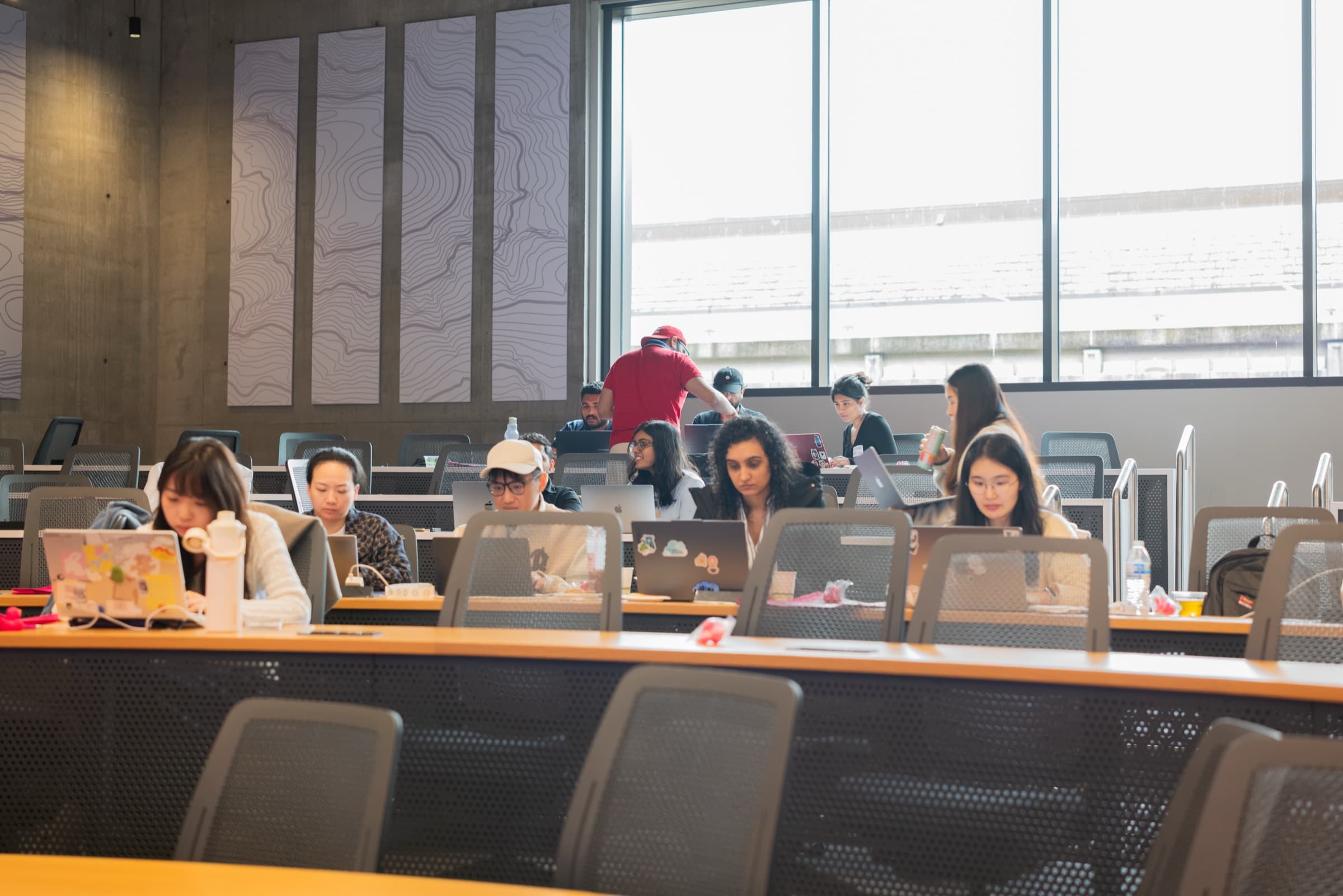 Several rows of participants working on laptops in a classroom.