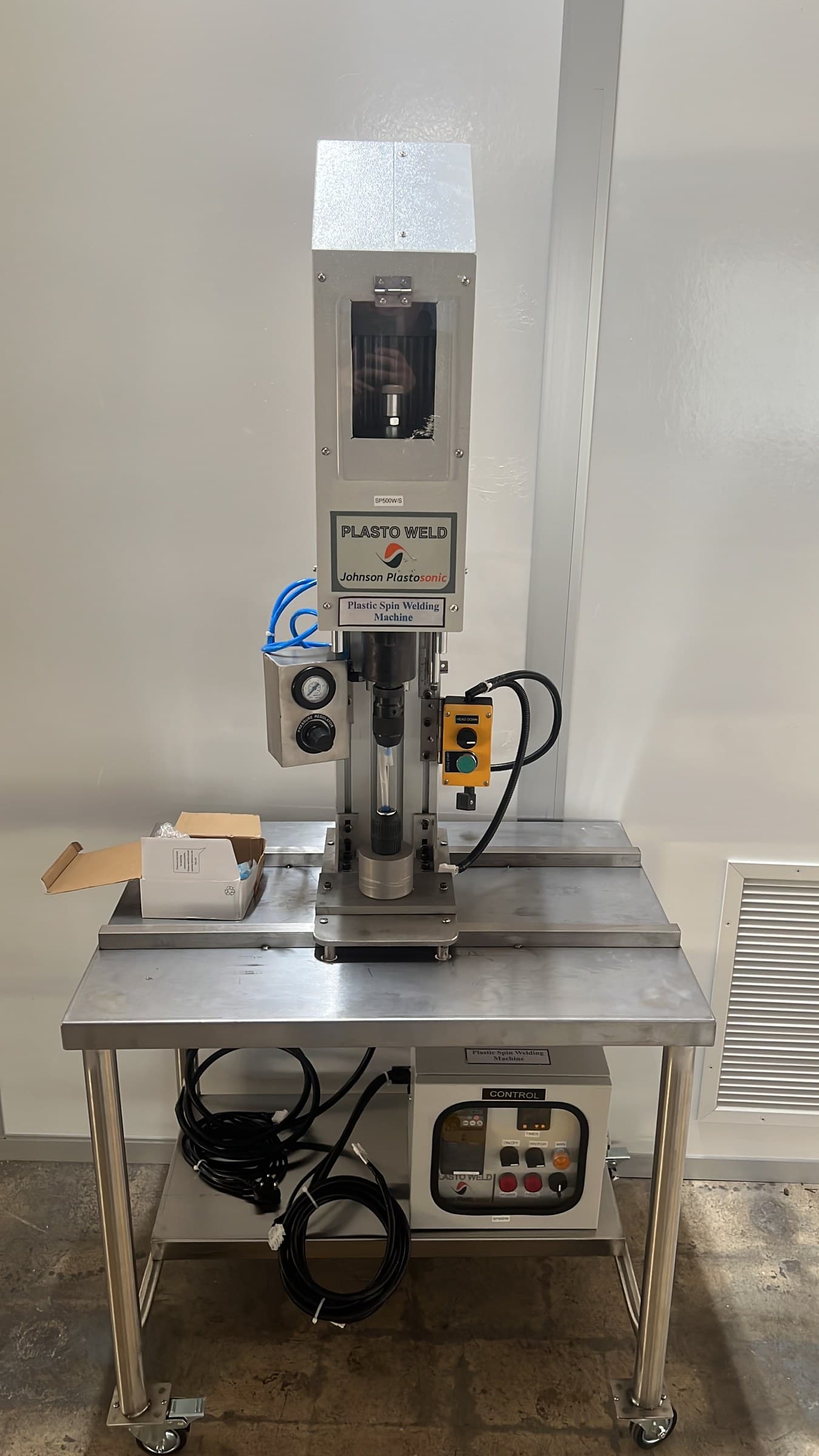 Plastic spin-welding machine on a stainless steel worktable.