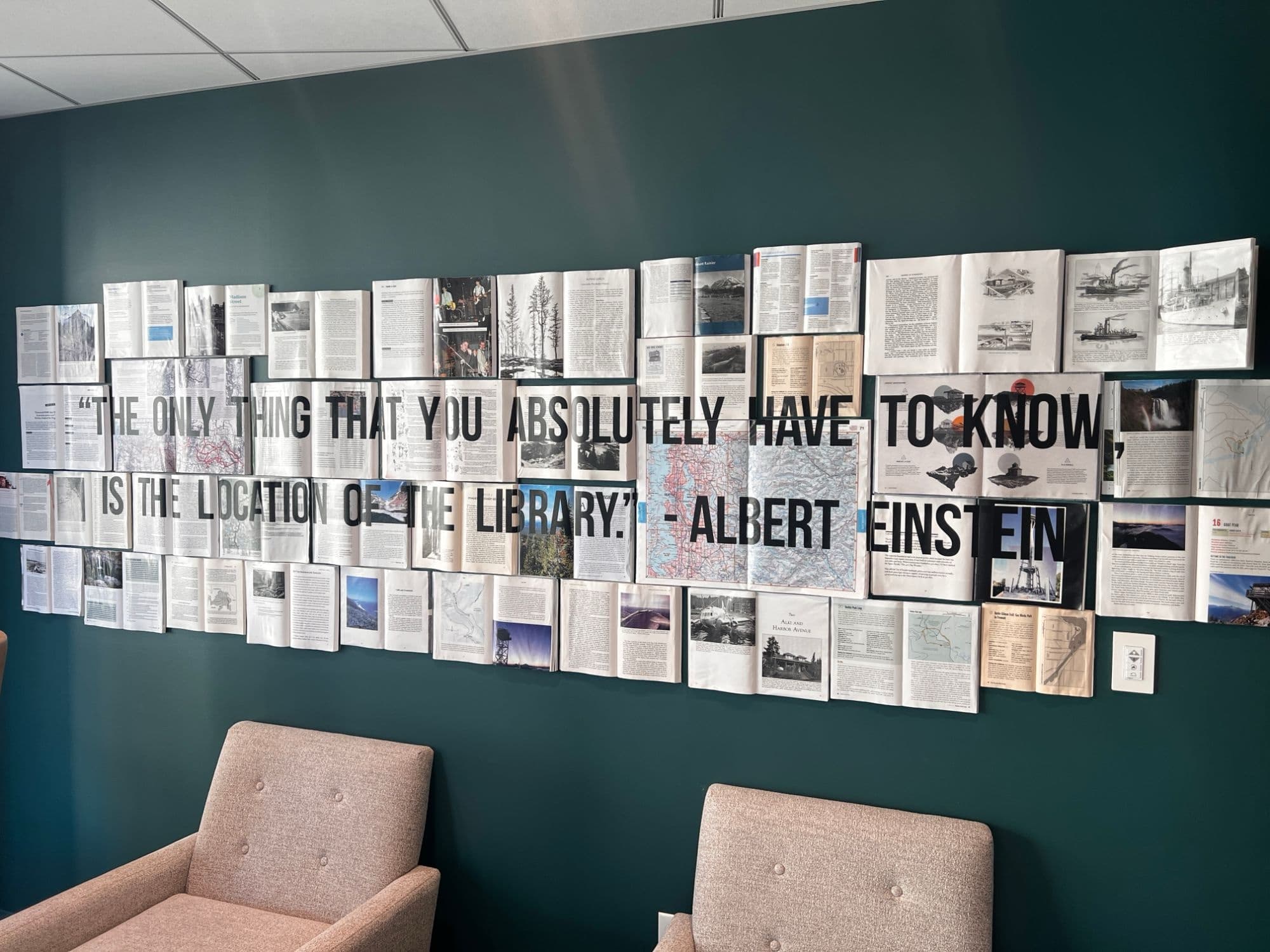 A wall of open books with an Albert Einstein quote about knowing the location of the library.