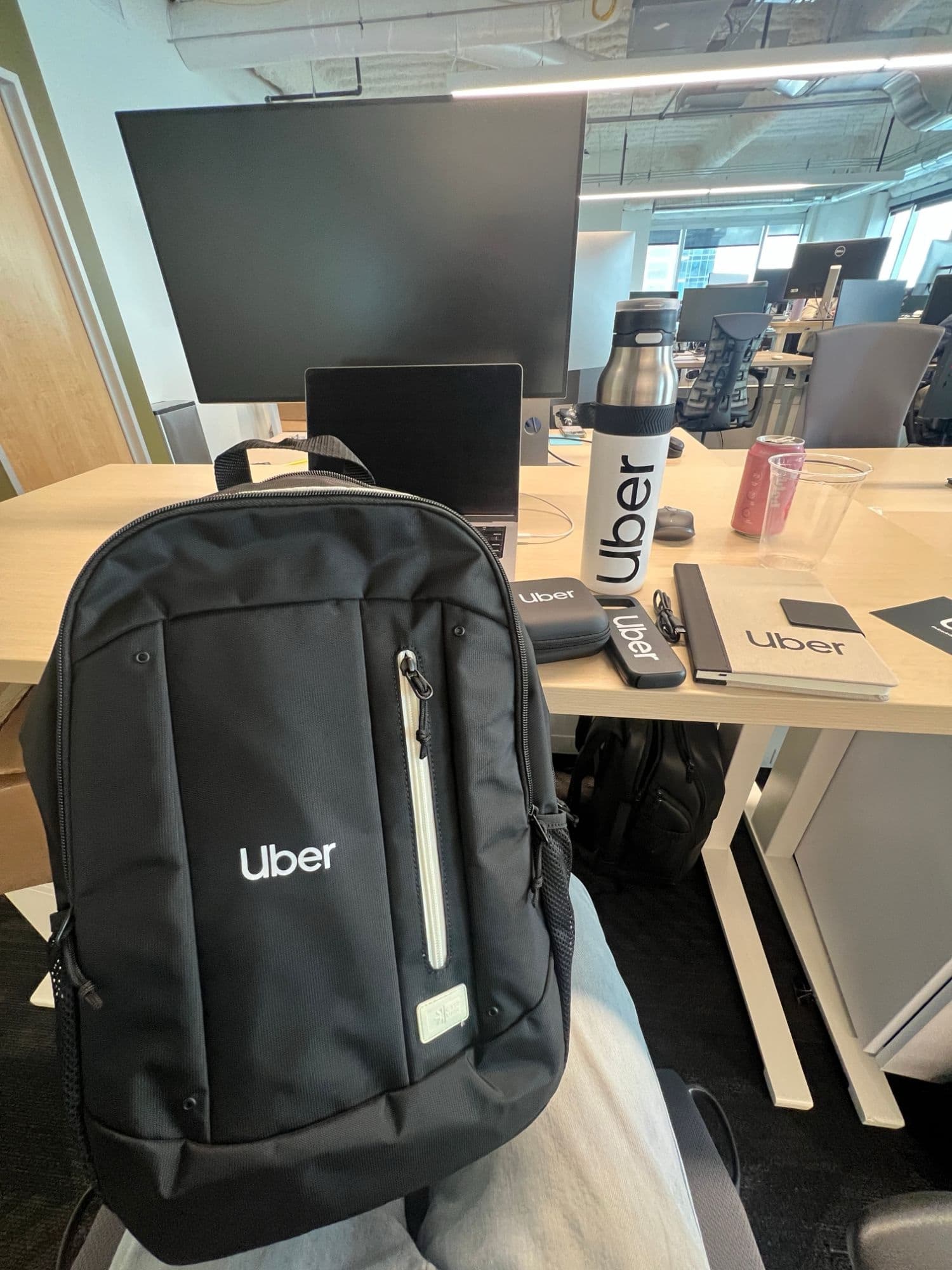 An Uber backpack, water bottle, notebook, and accessories on a desk in the Uber office.