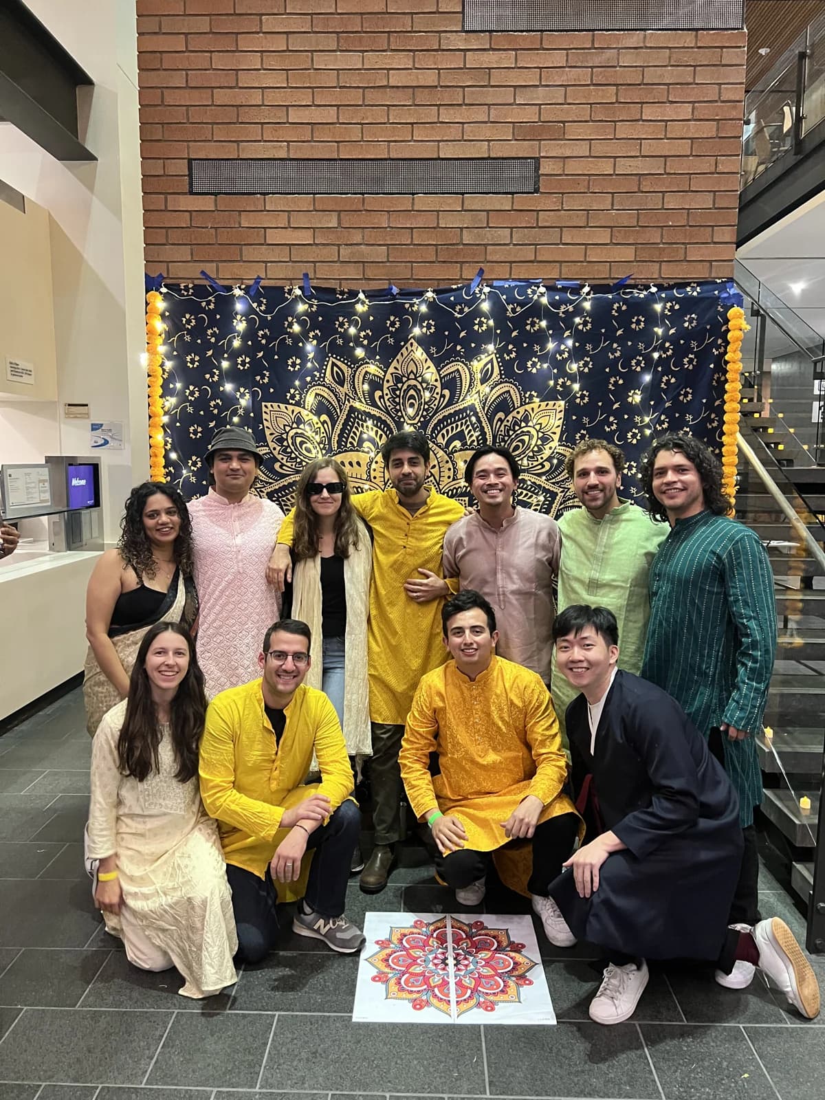 A group of classmates posing together in front of the Diwali backdrop.