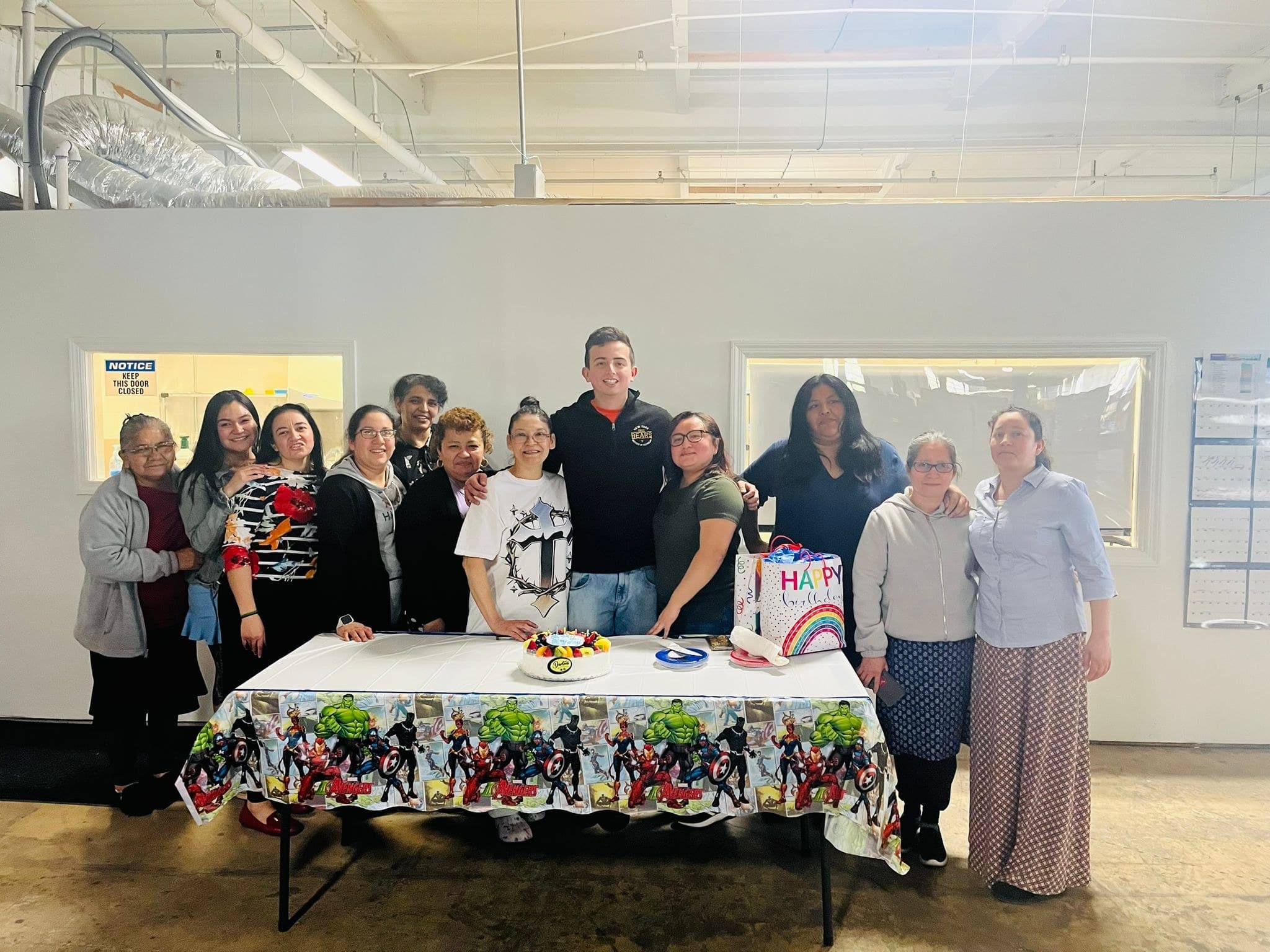 Empire colleagues gathered behind a decorated table with a birthday cake.